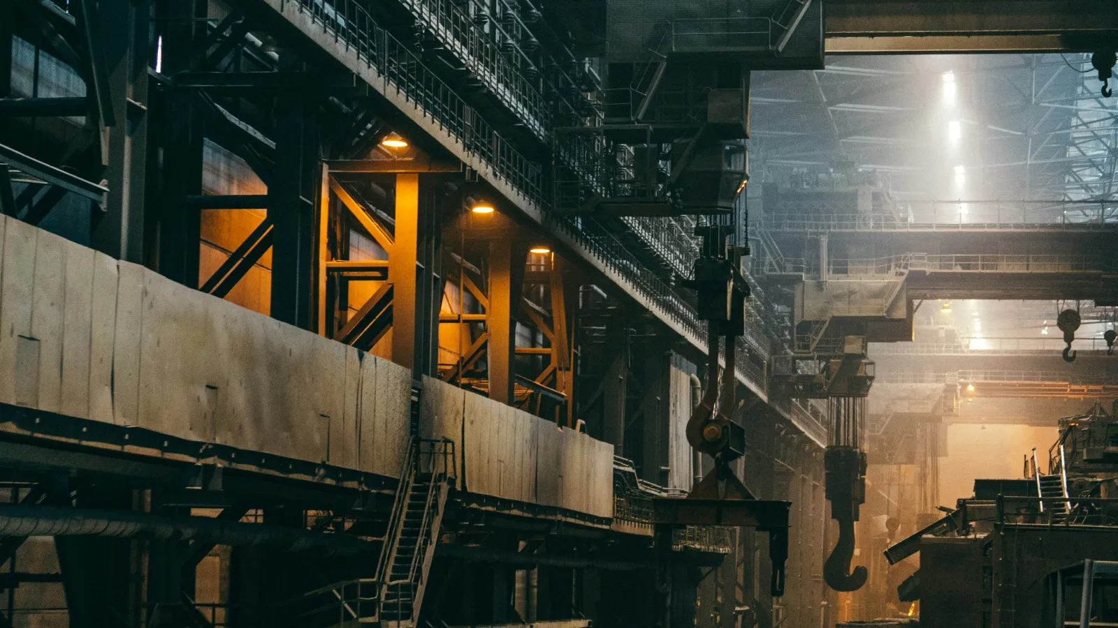 Inside a large metal industry plant with cranes and steel structures